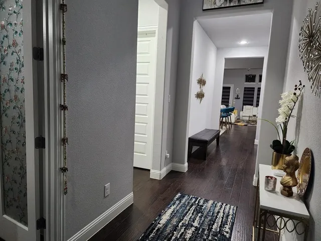 a view of a hallway with wooden floor and a cabinet