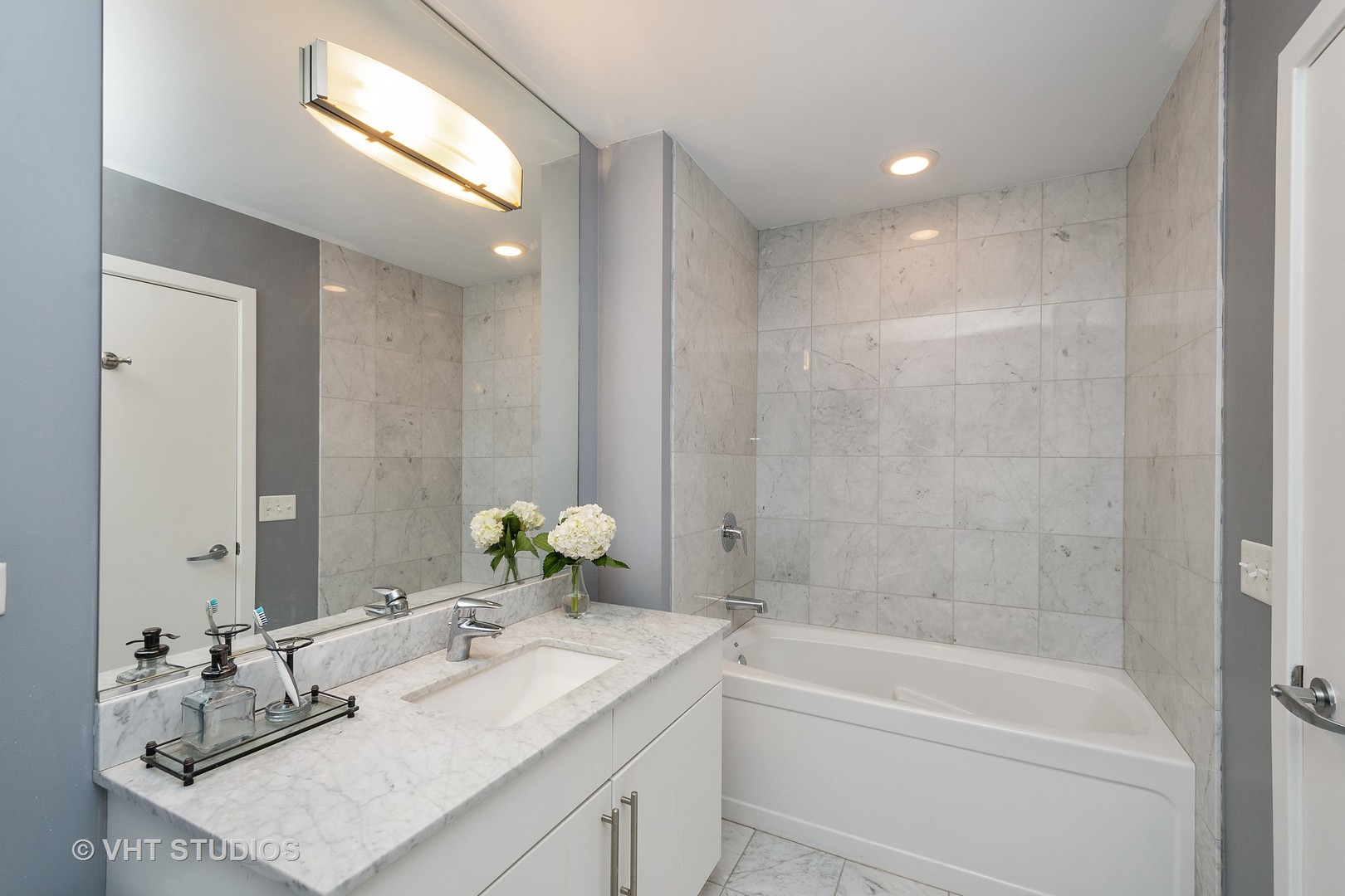 123 South Green Street, Unit 909B Chicago, IL 60607 - Photo 7 of 11 a bathroom with a granite countertop sink mirror and a bathtub