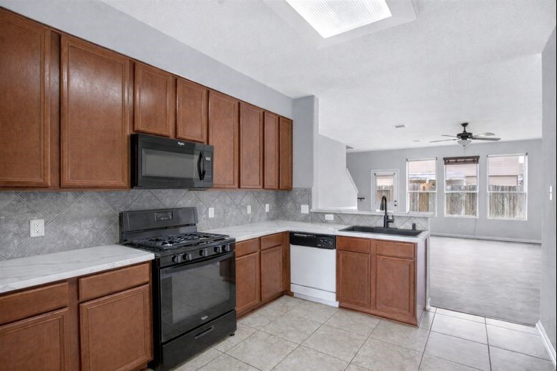1726 Sun Point Court Humble, TX 77396 - Photo 3 of 26 a kitchen with stainless steel appliances granite countertop wooden cabinets a sink and dishwasher