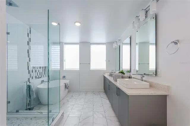 a spacious bathroom with a double vanity sink a mirror a bathtub and next to a window