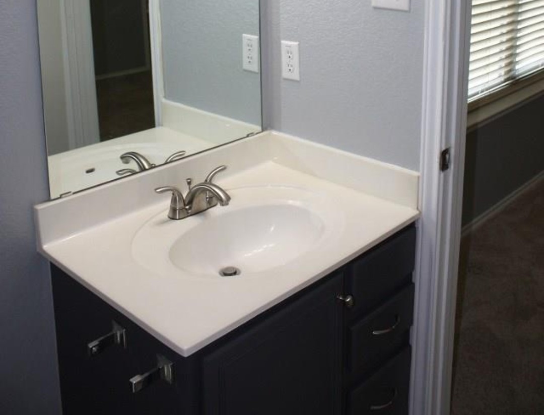 1120 Apollo Circle Round Rock, TX 78664 - Photo 3 of 14 Bathroom vanity featuring an integrated sink, brushed nickel faucet, and a large wall-mounted mirror
