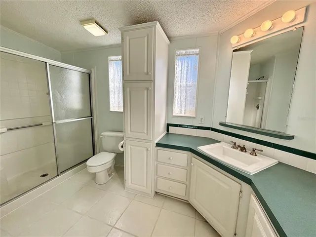 a bathroom with a granite countertop sink toilet and shower