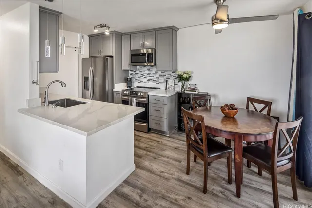 a kitchen with stainless steel appliances kitchen island a table chairs and refrigerator