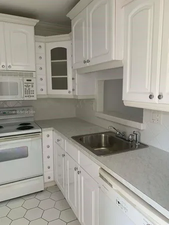 a kitchen with white cabinets and white appliances