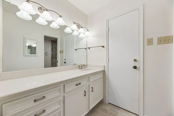 a spacious bathroom with double sink a mirror and a light fixture