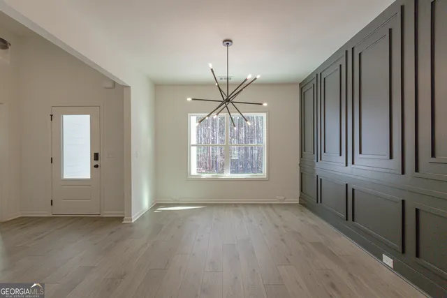 a view of an empty room with a window and a kitchen