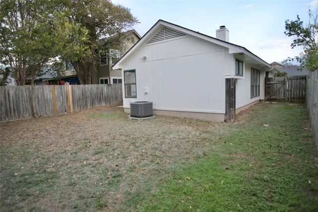 a view of backyard of house with wooden fence