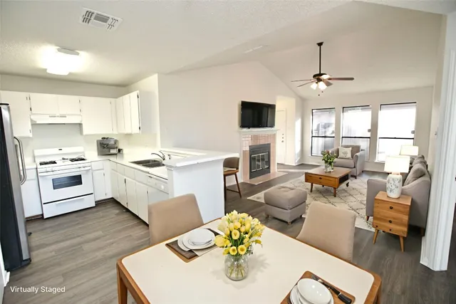 a kitchen that has a sink a stove top oven a dining table and chairs