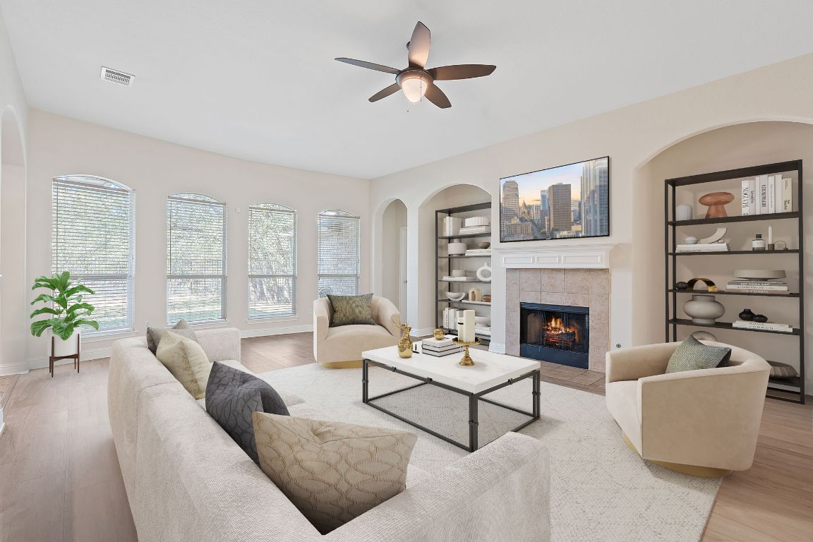 Living room featuring light wood-type flooring, built in features, ceiling fan, and visible vents