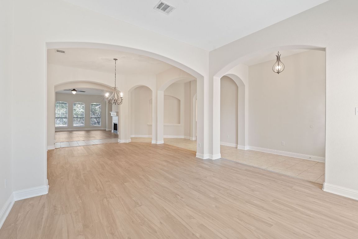 738 Nelson Ranch Road Cedar Park, TX 78613 - Photo 13 of 35 Empty room with arched walkways, ceiling fan with notable chandelier, baseboards, visible vents, and light wood-style floors