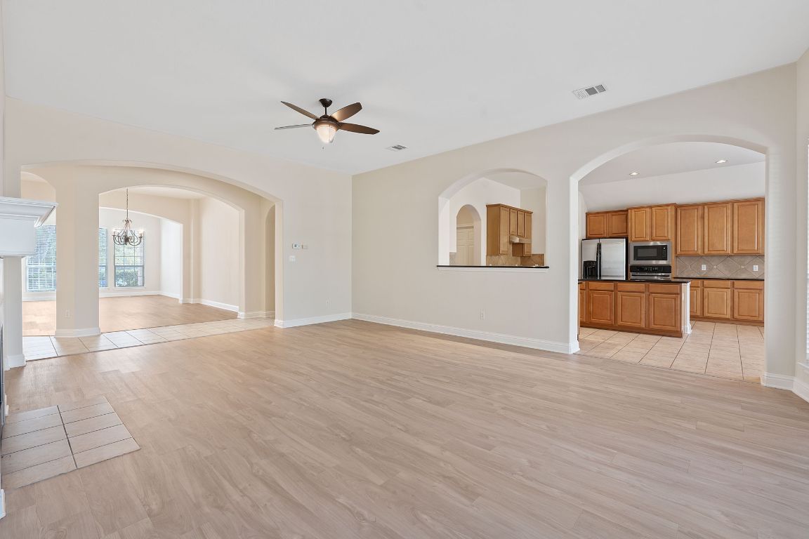 738 Nelson Ranch Road Cedar Park, TX 78613 - Photo 16 of 35 Unfurnished living room with light wood finished floors, ceiling fan with notable chandelier, visible vents, and baseboards
