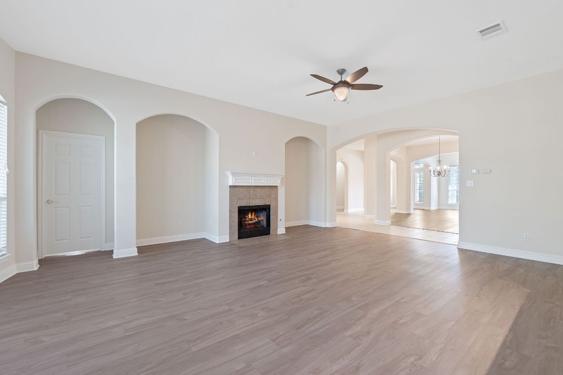 738 Nelson Ranch Road Cedar Park, TX 78613 - Photo 17 of 35 Unfurnished living room with visible vents, light wood-style flooring, a ceiling fan, and a tile fireplace