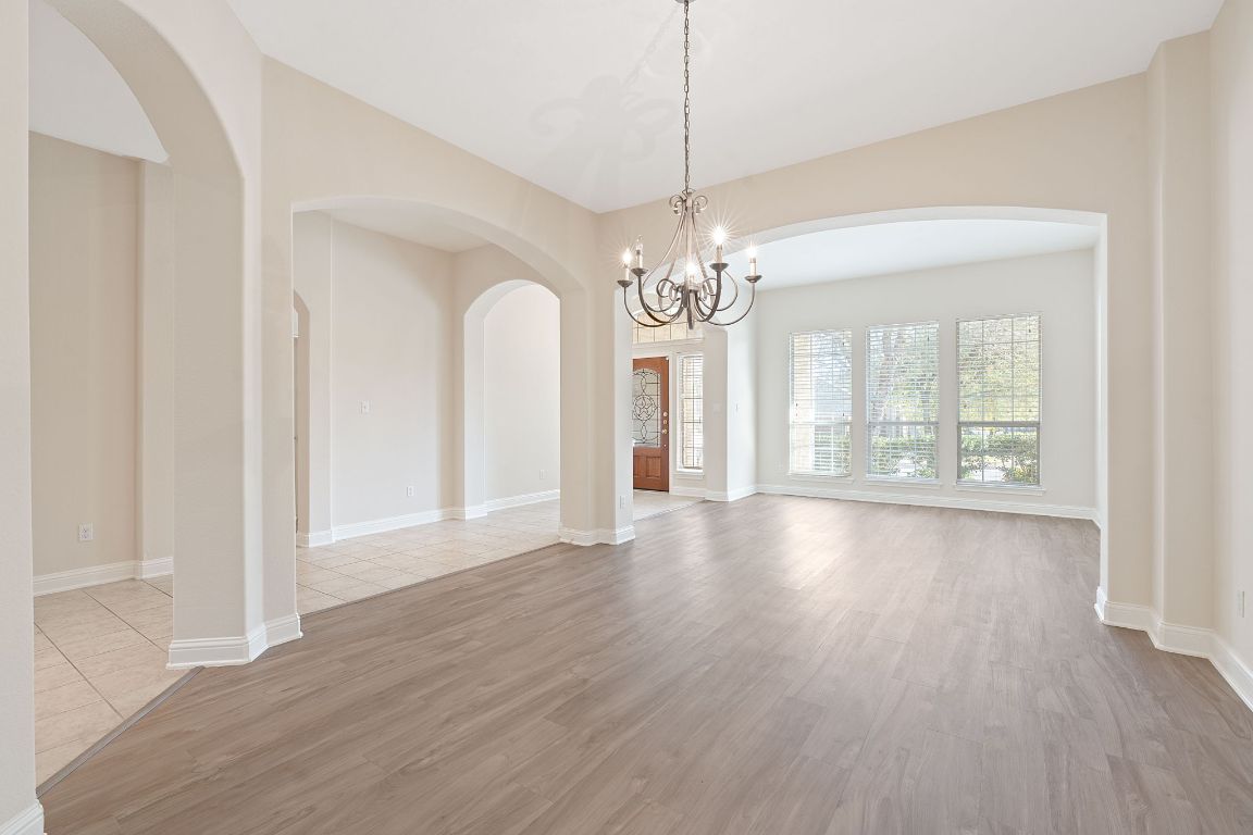 738 Nelson Ranch Road Cedar Park, TX 78613 - Photo 6 of 35 Empty room featuring light wood-style flooring, baseboards, a notable chandelier, and arched walkways