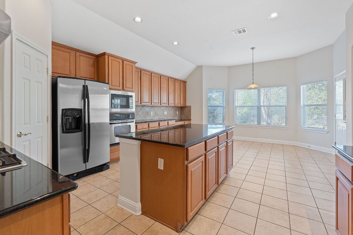 738 Nelson Ranch Road Cedar Park, TX 78613 - Photo 8 of 35 Kitchen featuring light tile patterned flooring, visible vents, stainless steel appliances, a center island, and backsplash