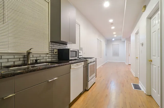 a kitchen with stainless steel appliances granite countertop a sink a stove and a wooden floors