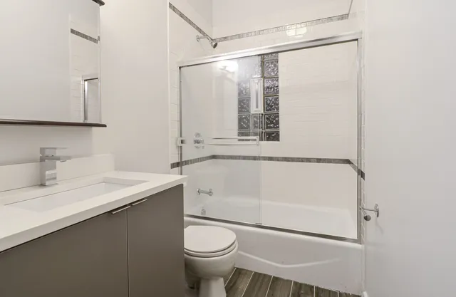a bathroom with a granite countertop sink mirror vanity and toilet
