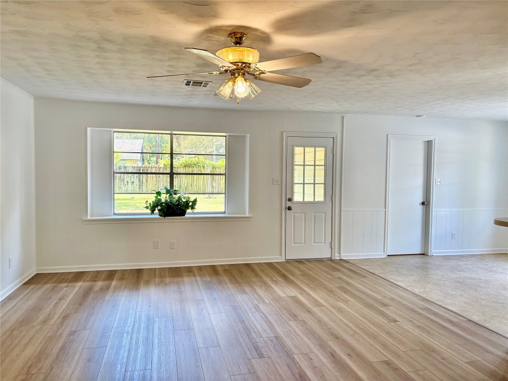 1111 Burning Tree Road Kingwood, TX 77339 - Photo 13 of 32 This bright and inviting room features LVP flooring, a ceiling fan, and natural light from a large window and glass-paneled door. The open layout offers a versatile space for entertaining.