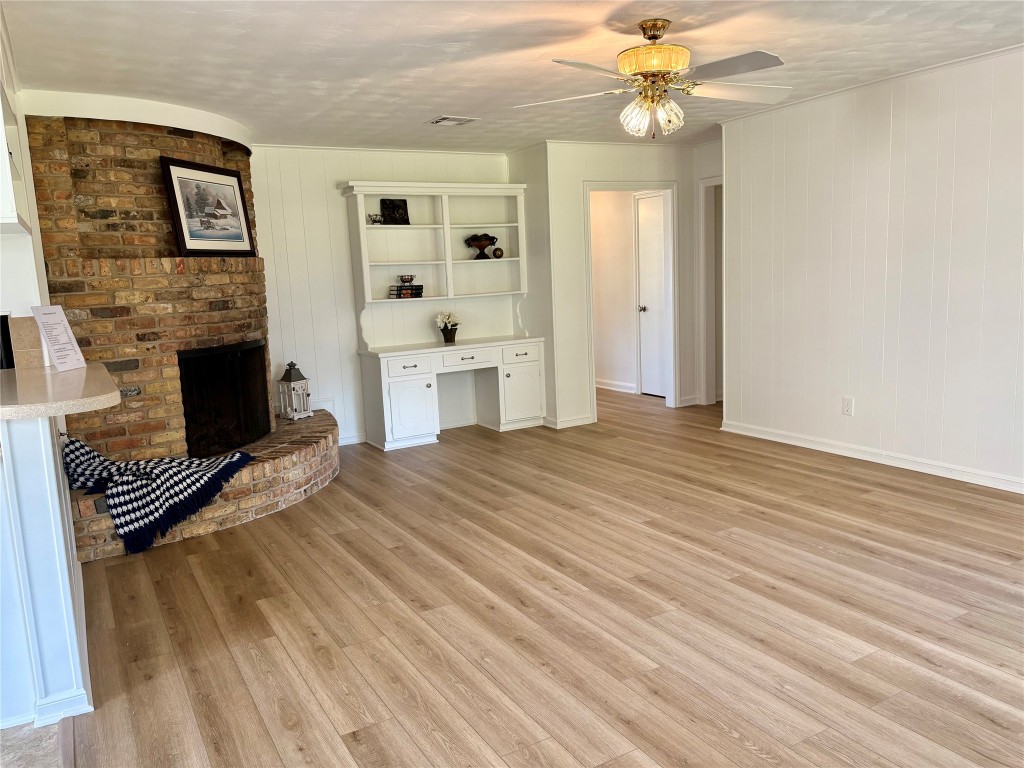 1111 Burning Tree Road Kingwood, TX 77339 - Photo 15 of 32 This inviting living room features a cozy corner brick fireplace and a built-in desk with shelving. The neutral walls and ceiling fan create a warm and welcoming atmosphere.