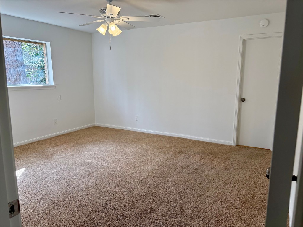 1111 Burning Tree Road Kingwood, TX 77339 - Photo 22 of 32 Tranquil primary bedroom featuring a large window with serene views, plush carpeting, and a ceiling fan for comfort.