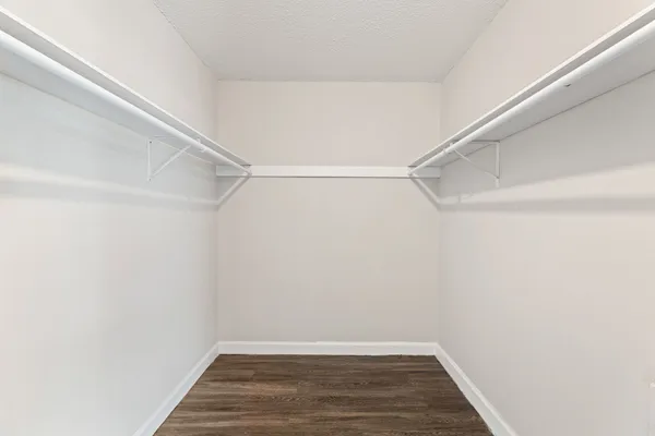 a view of an empty room with wooden floor and a ceiling fan