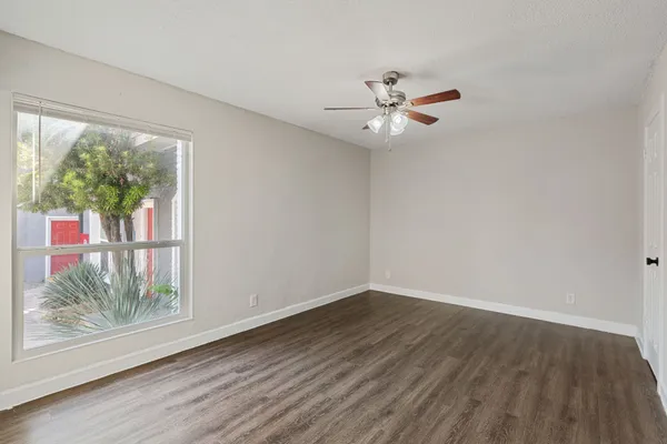 a view of an empty room with a window and wooden floor