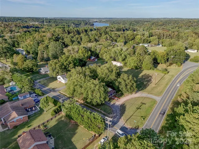an aerial view of a residential houses with outdoor space and trees