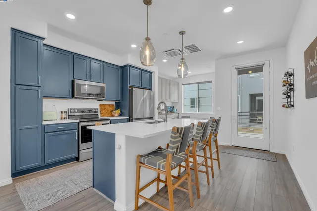 a kitchen with stainless steel appliances a dining table chairs stove and refrigerator