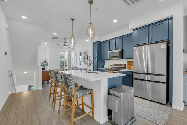 a kitchen with stainless steel appliances a dining table chairs refrigerator and microwave