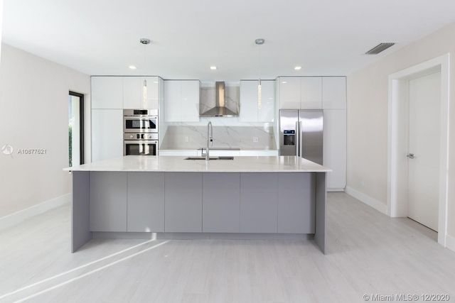 a large white kitchen with kitchen island white cabinets and refrigerator