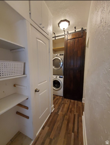 320 South State Street Preston, ID 83263 - Photo 9 of 20 Laundry area featuring a barn door, a textured ceiling, dark wood-style floors, stacked washer and clothes dryer, and a textured wall
