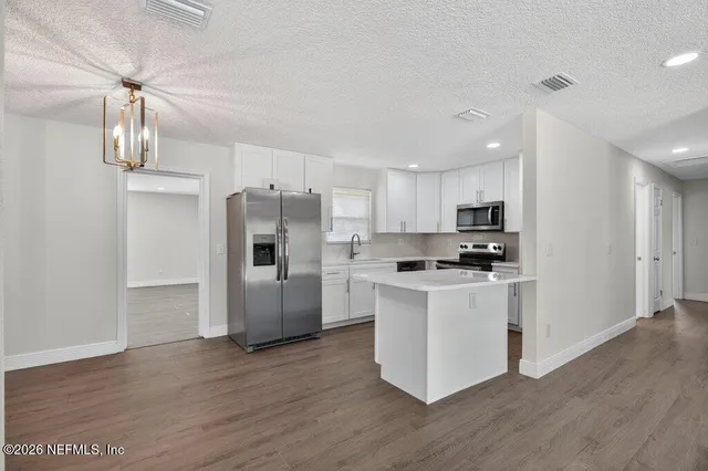 a kitchen with stainless steel appliances granite countertop a refrigerator a stove top oven a sink and dishwasher