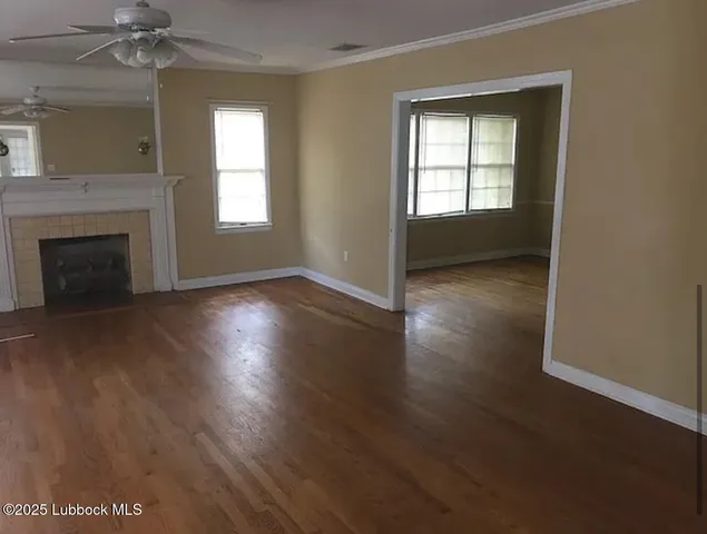 an empty room with wooden floor fireplace and windows