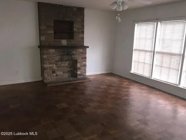 an empty room with windows fireplace and wooden floor