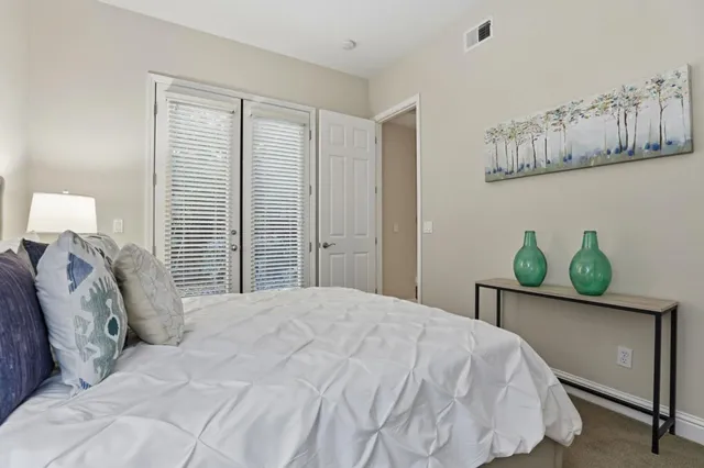 a spacious bedroom with a bed table and a window