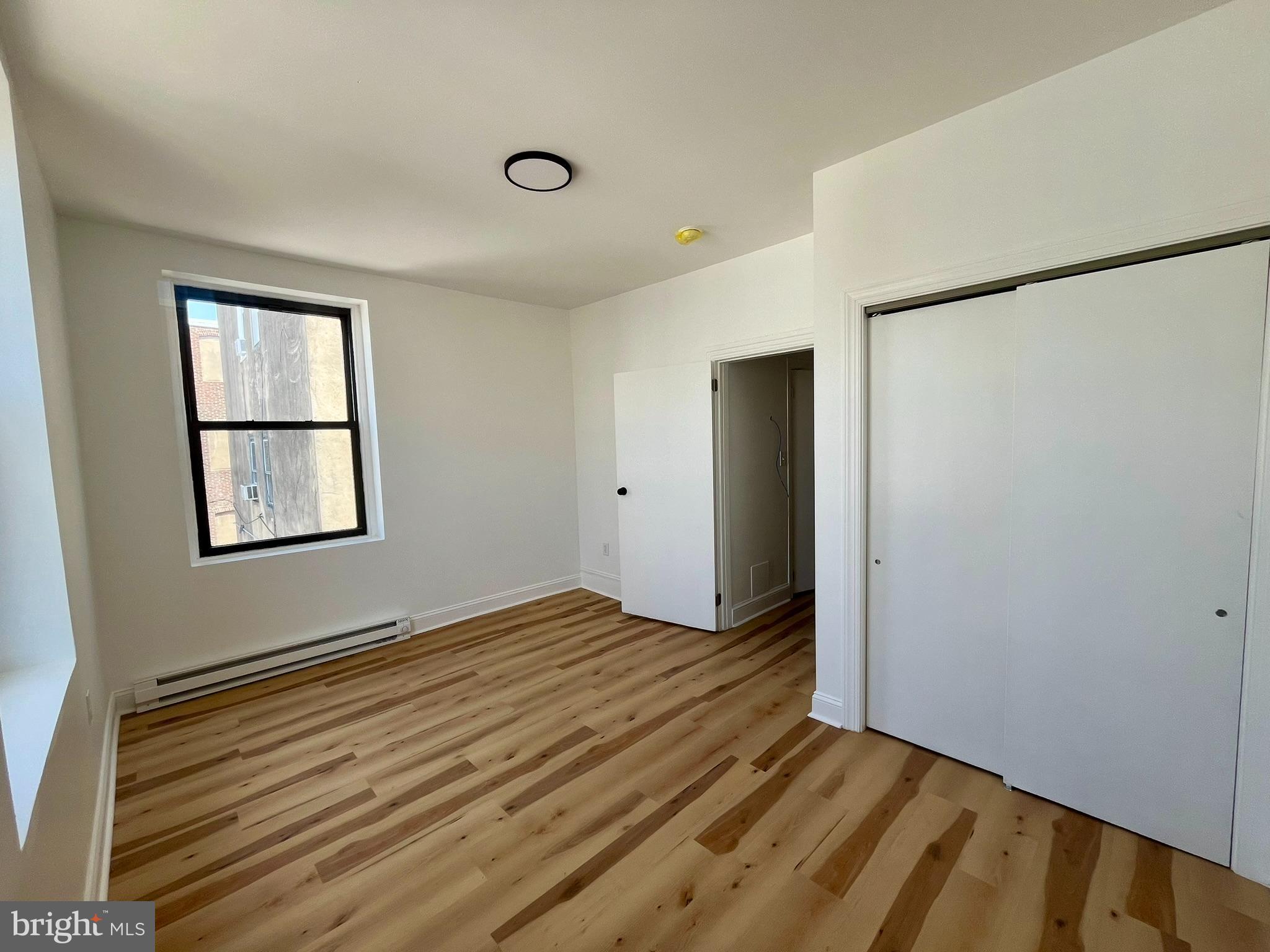 4413 Walnut Street, Unit 2R Philadelphia, PA 19104 - Photo 3 of 18 a view of an empty room with wooden floor and a window