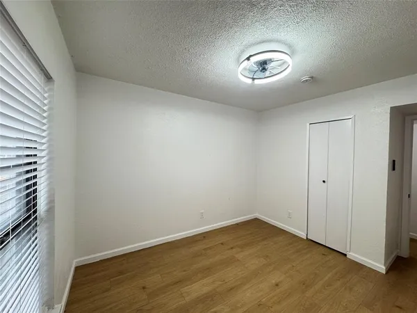 an empty room with a chandelier fan and wooden floor