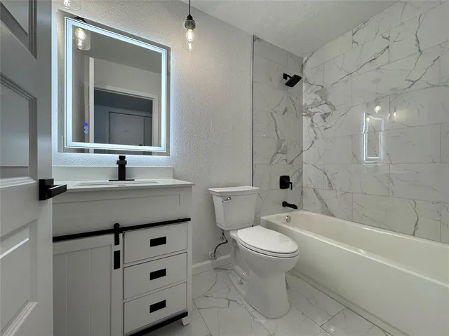 a bathroom with a granite countertop sink toilet mirror and bathtub