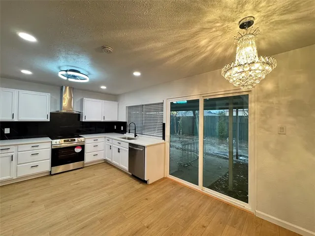 a kitchen with stainless steel appliances granite countertop a stove top oven a sink dishwasher a refrigerator and a fireplace with wooden floor