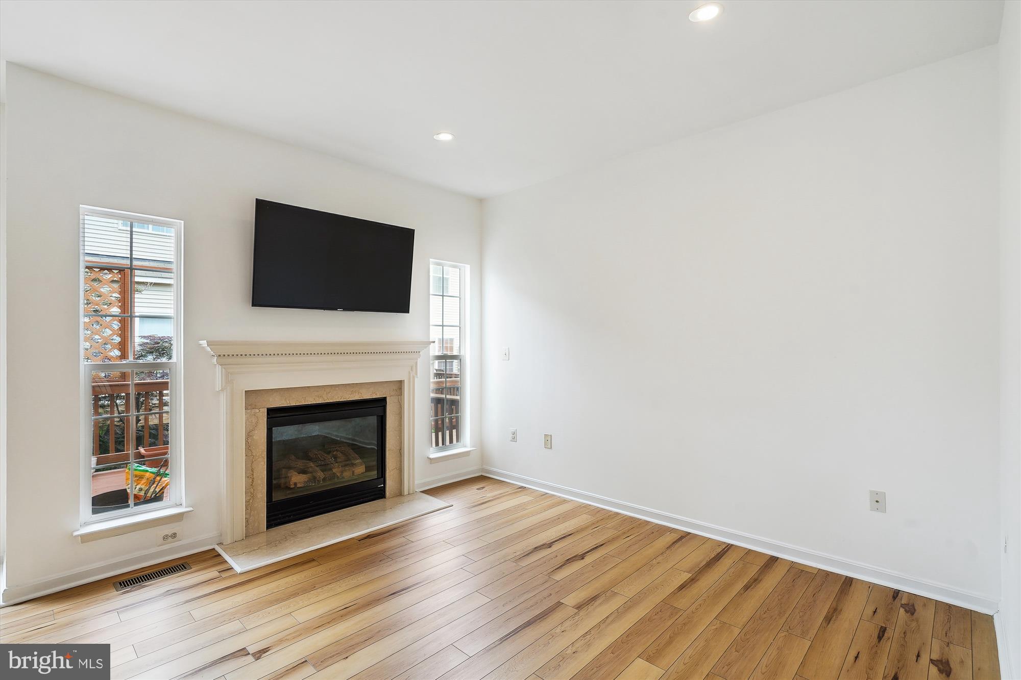 6688 Roderick Loop Gainesville, VA 20155 - Photo 11 of 40 a view of an empty room with wooden floor fireplace and a window