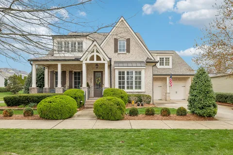 a front view of a house with a yard and potted plants
