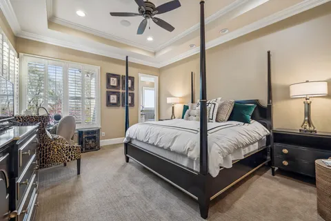 a spacious bedroom with a bed a dresser and a chandelier