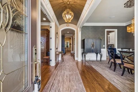 a view of a hallway with wooden floor a chandelier