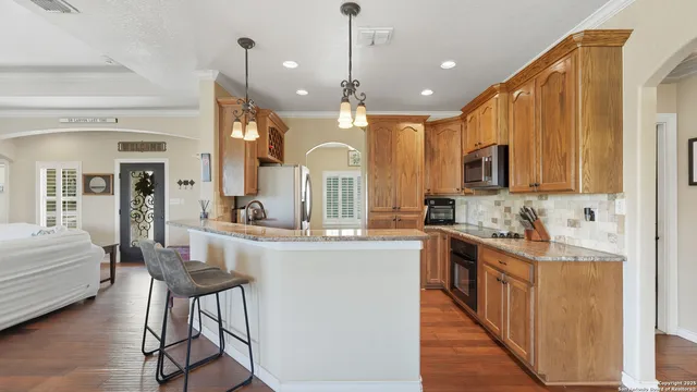 a kitchen with kitchen island granite countertop wooden cabinets and white appliances