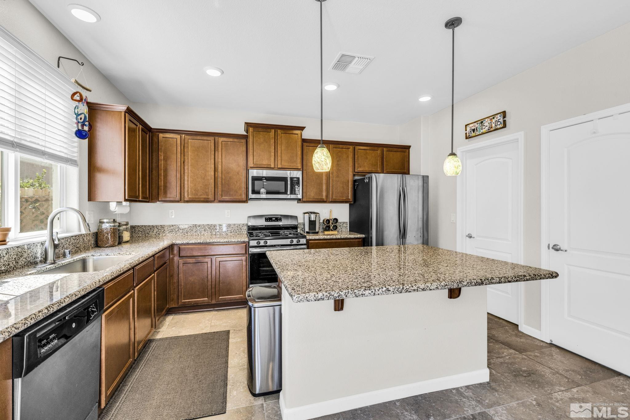 2215 Symphony Way Reno, NV 89521 - Photo 2 of 39 a kitchen with stainless steel appliances granite countertop wooden cabinets a sink a stove a refrigerator and island