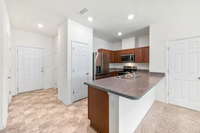 a kitchen with kitchen island a counter top space cabinets and stainless steel appliances