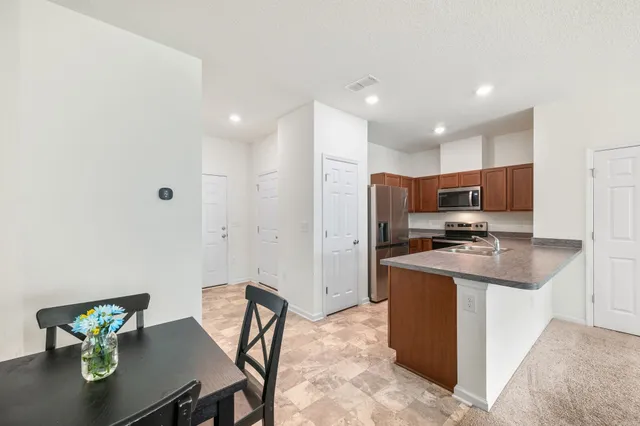a kitchen with stainless steel appliances kitchen island granite countertop a sink and a refrigerator