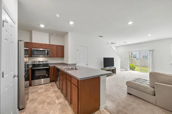 a large kitchen with stainless steel appliances granite countertop a stove top oven a sink dishwasher a dining table and chairs