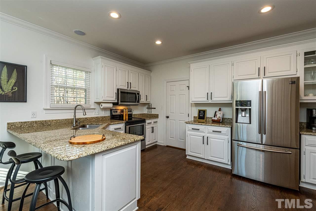 8105 Iron Bark Court Raleigh, NC 27606 - Photo 11 of 30 a kitchen with refrigerator a stove a sink dishwasher a refrigerator and a dining table with wooden floor