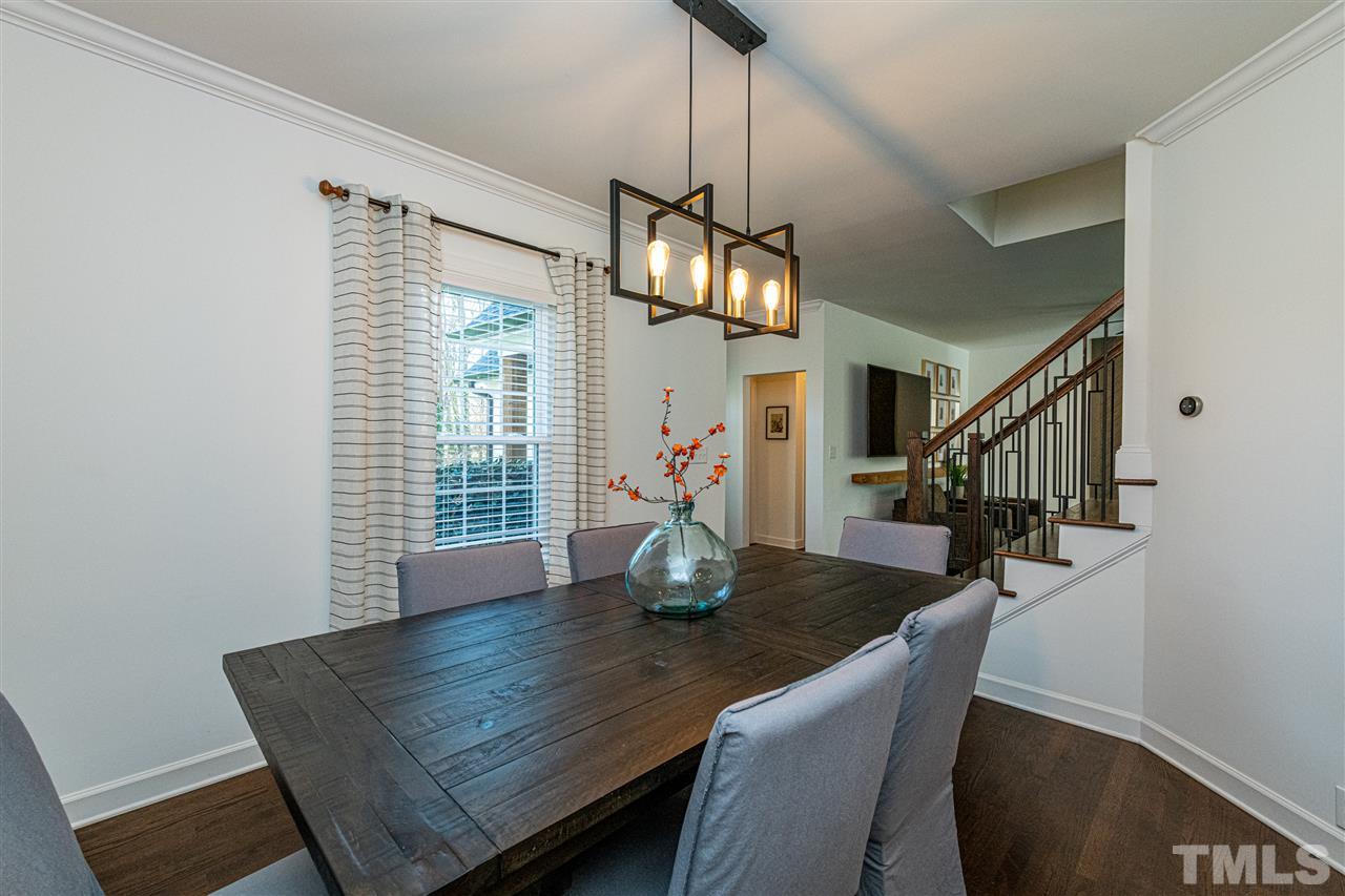 8105 Iron Bark Court Raleigh, NC 27606 - Photo 8 of 30 a dining room with wooden floor a chandelier a wooden table and chairs