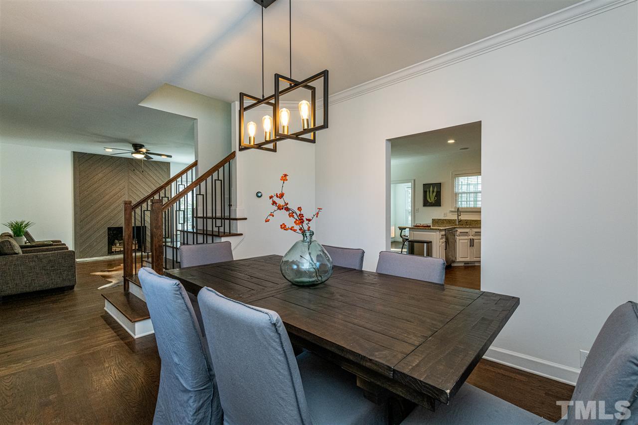 8105 Iron Bark Court Raleigh, NC 27606 - Photo 9 of 30 a dining room with wooden floor a chandelier a wooden table and chairs